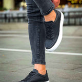 Black low-top sneakers with white sole, black laces, and perforated upper