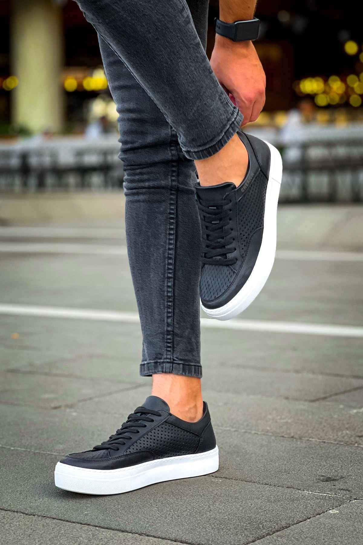 Black low-top sneakers with white sole, black laces, and perforated upper