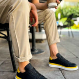 Men's black sneakers with yellow trim and white rubber sole, side view
