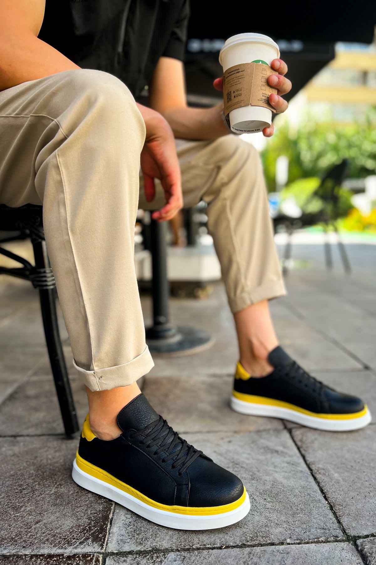 Men's black sneakers with yellow trim and white rubber sole, side view