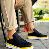 Men's black low-top sneakers with yellow accents and white sole, angled side