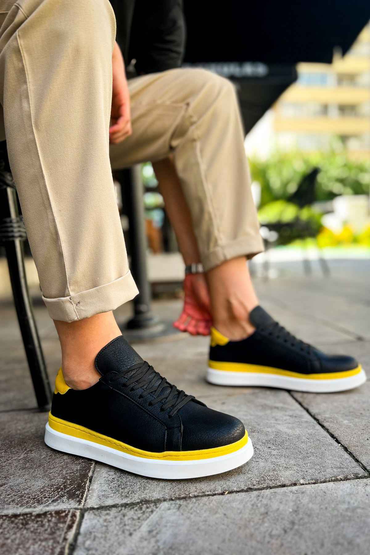 Men's black low-top sneakers with yellow accents and white sole, angled side