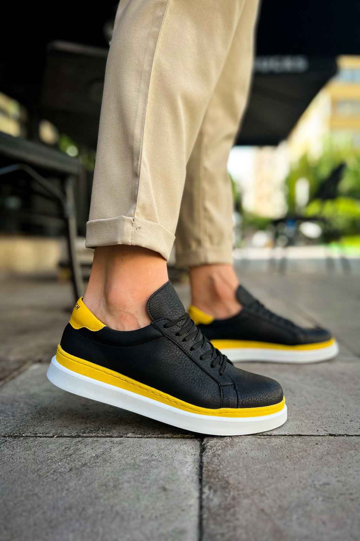 Men's black sneakers with yellow toe detail and white sole, front side view