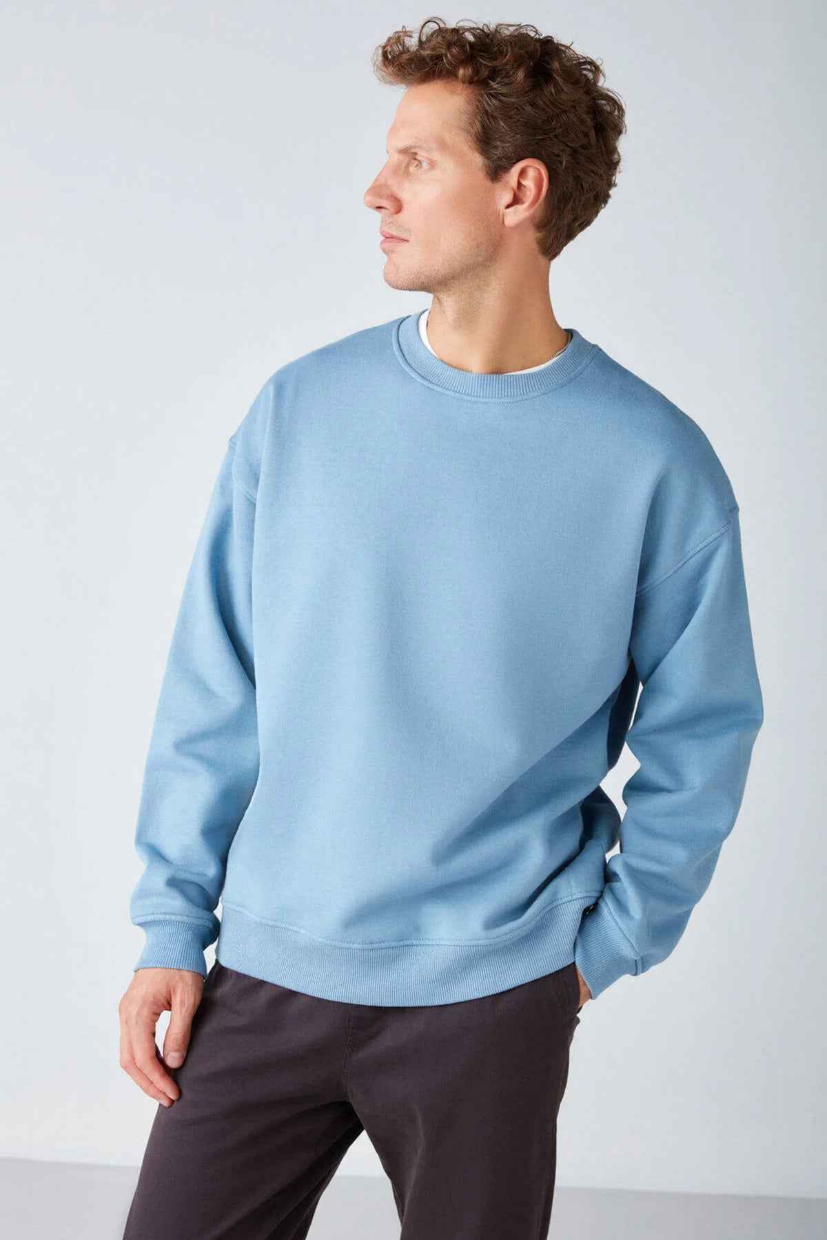 Men's oversized light blue sweatshirt, three-quarter view showing crew neck and hem