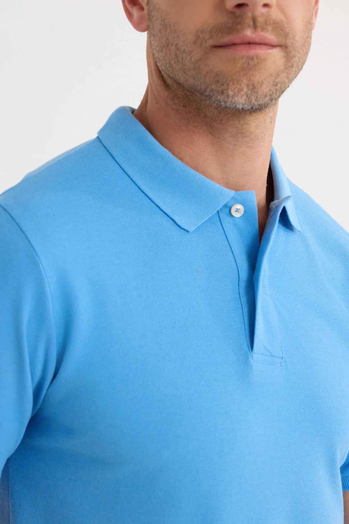 Blue polo shirt collar detail with button and stitched placket