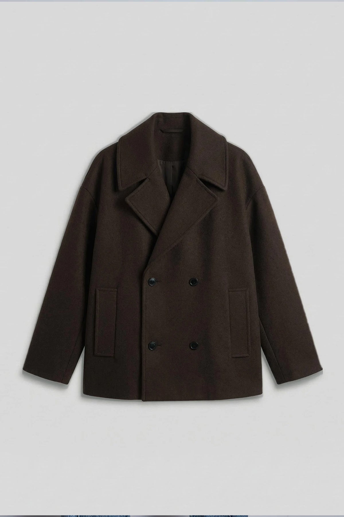 Dark brown oversized double-breasted coat with notch lapels and flap pockets.