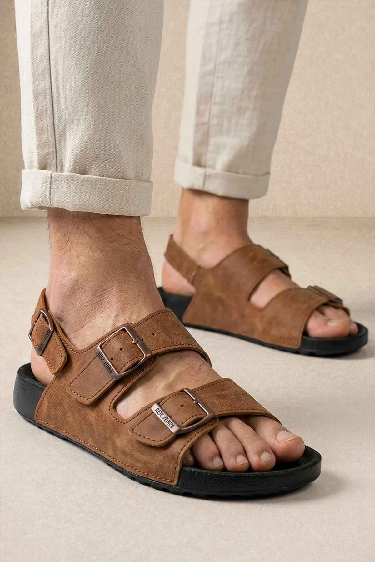 Brown suede sandals with two adjustable buckled straps and open toe, black rubber sole