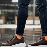 Men's brown sneakers with white treaded sole, lace-up eyelets, and stitching
