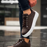 Men's brown lace-up sneakers with thick white sole on one foot