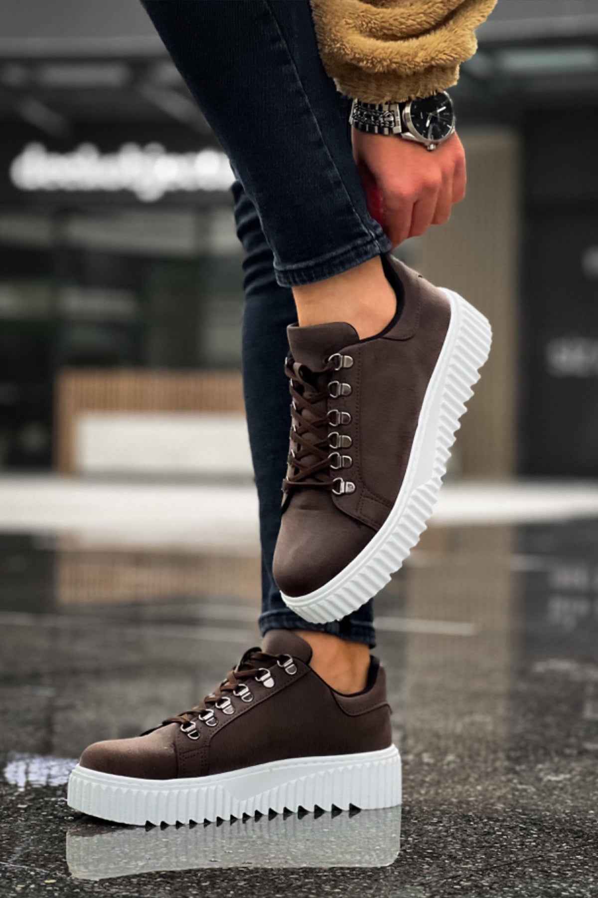 Men's brown lace-up sneakers with thick white sole on one foot
