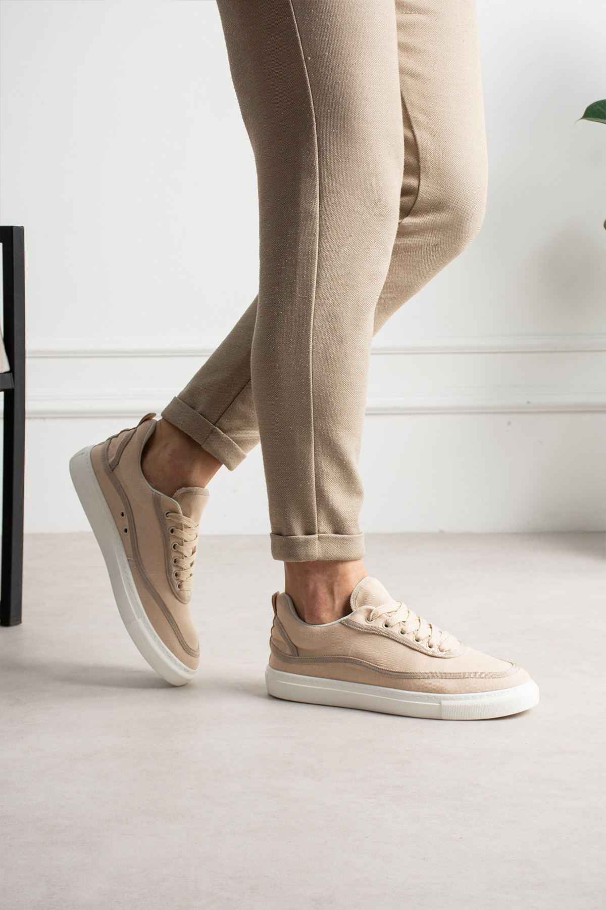 Men's beige canvas sneakers with white rubber sole, lace-up front, side stitching.