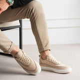 Men's beige canvas sneakers shown from side, lace-up, white rubber sole, minimal branding.