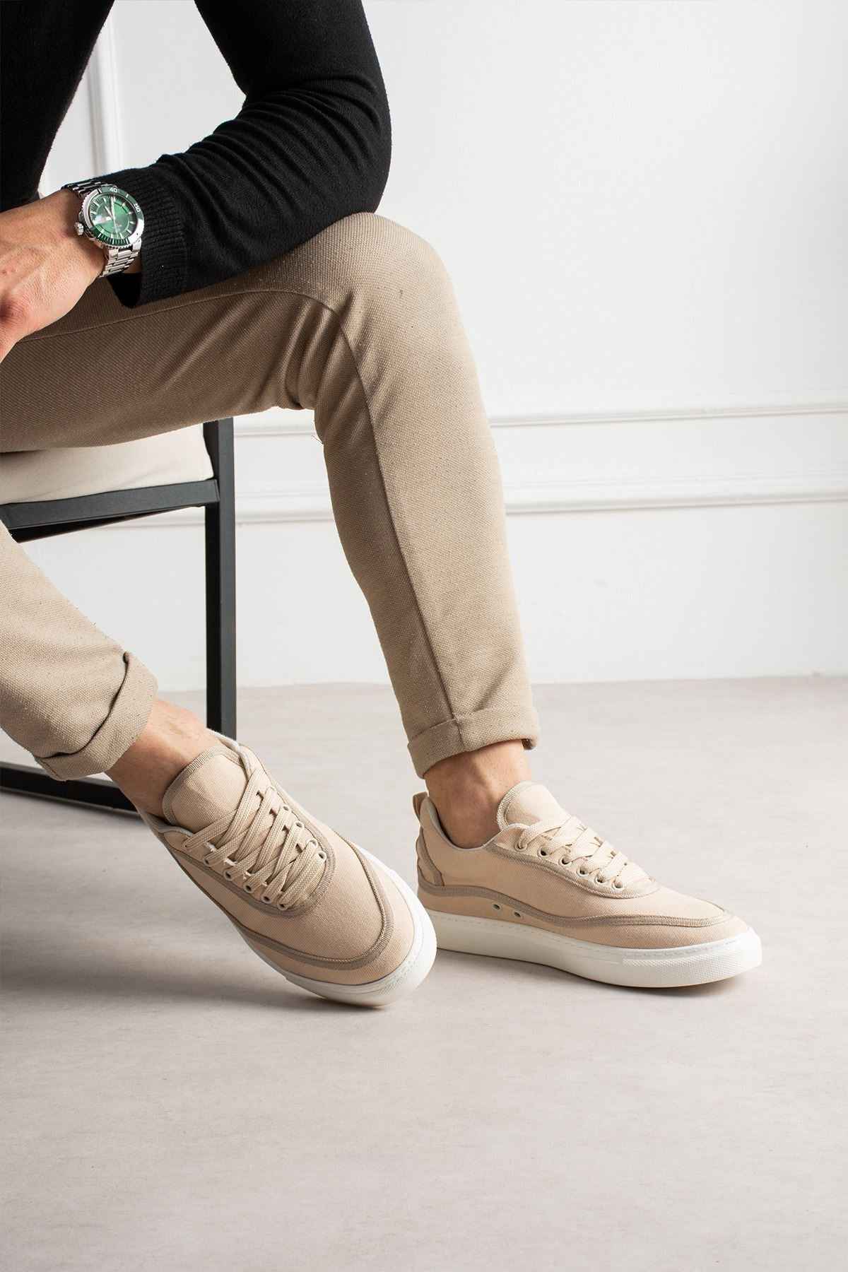 Men's beige canvas sneakers shown from side, lace-up, white rubber sole, minimal branding.