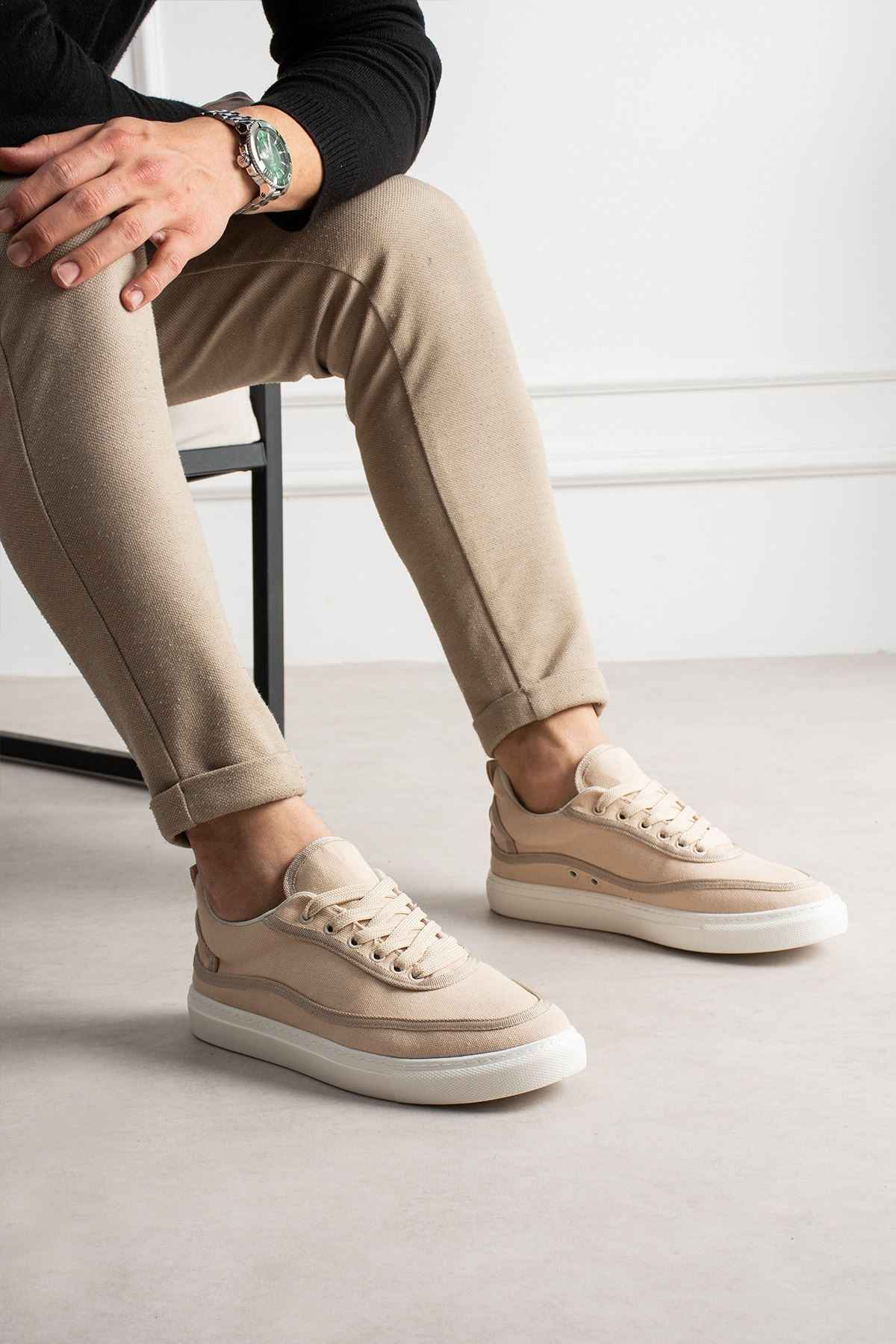Men's beige canvas sneakers, front three-quarter view with lace-up vamp and white sole.
