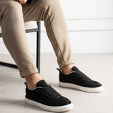 Men's black lace-up canvas sneakers, side view on feet, white cupsole