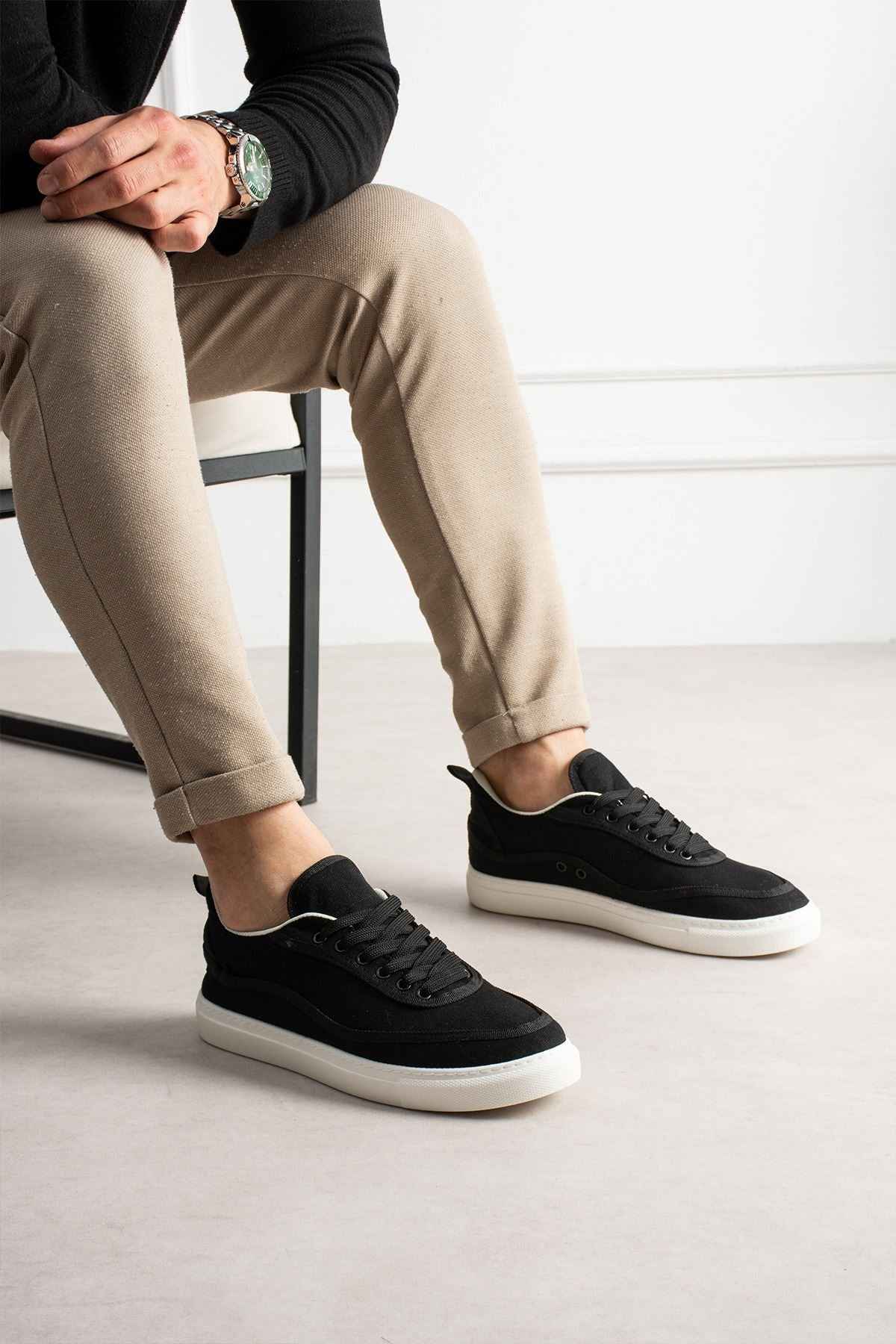 Men's black lace-up canvas sneakers, side view on feet, white cupsole