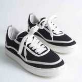 Black canvas low-top sneakers with white laces, side stripes, and rubber sole