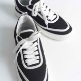 Pair of black canvas low-top sneakers with white laces and double side stripes