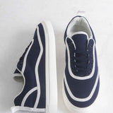 Pair of dark blue canvas sneakers with white stripes, laces, and white midsoles