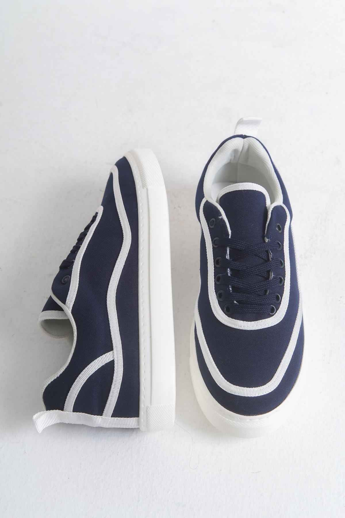 Pair of dark blue canvas sneakers with white stripes, laces, and white midsoles