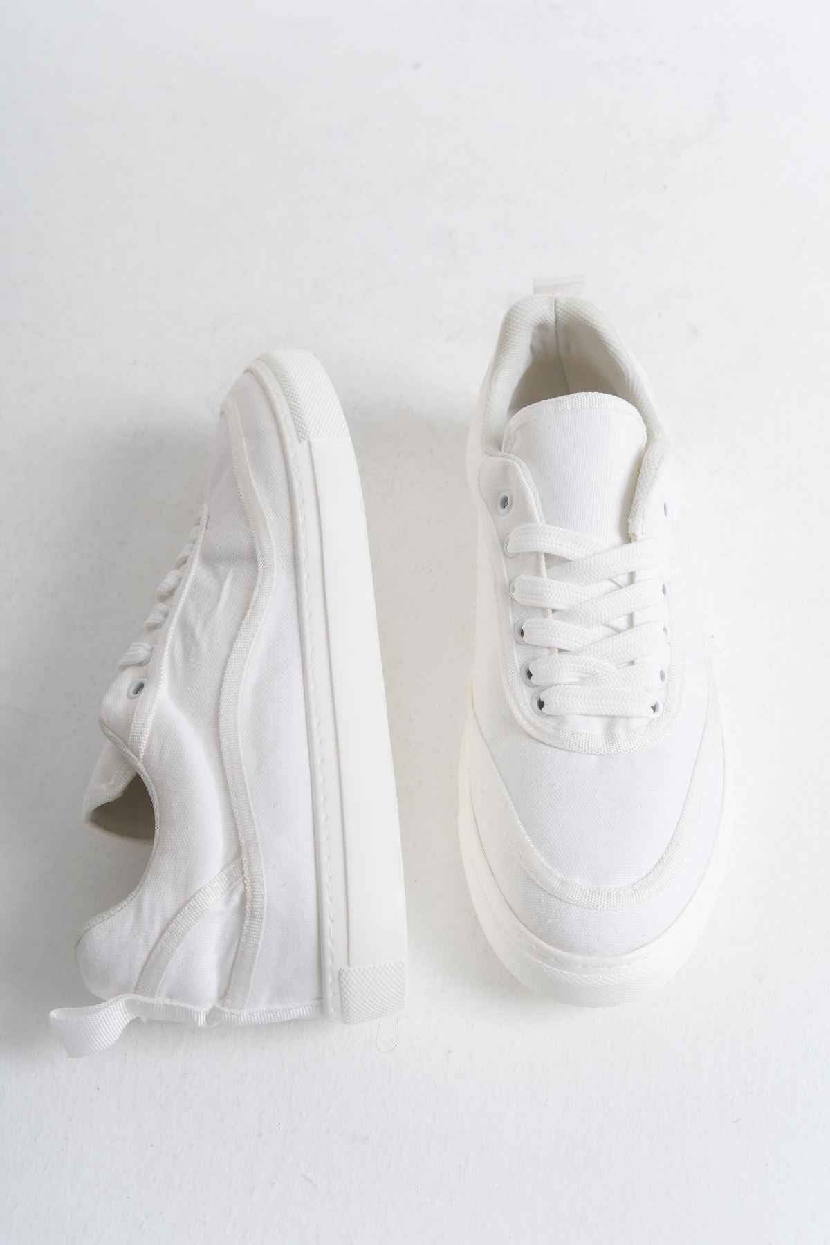 White canvas low-top sneakers with side profile and open heel