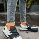 Men's casual sneakers with white panels and dark gray uppers; orange heel patch