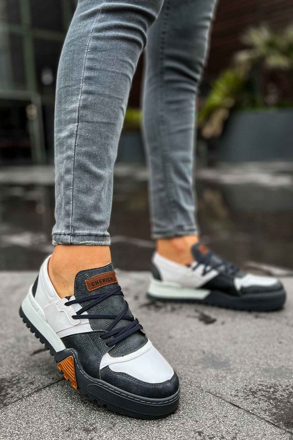 Men's casual sneakers with white panels and dark gray uppers; orange heel patch