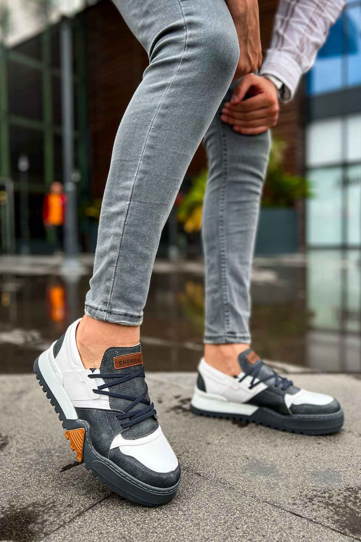 Casual sneakers in white and dark gray with lace-up front and orange heel patch