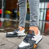 Casual sneakers with white toe, dark gray upper, lace-up design and orange heel patch