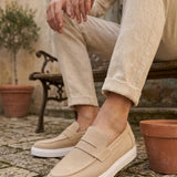 Men's beige suede loafer with strap, white sole, worn with light trousers