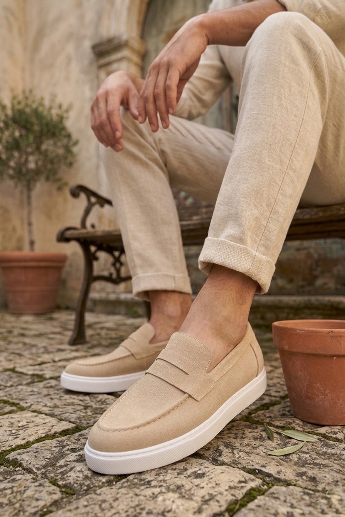 Men's beige suede loafer with strap, white sole, worn with light trousers