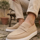 Men's beige suede loafer, front quarter view with saddle strap and white sole