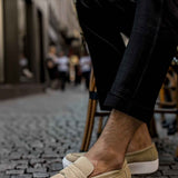 Beige suede men's loafers with slip-on strap and white rubber sole.