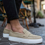 Beige suede loafers on feet, slip-on style with white sole and stitching.