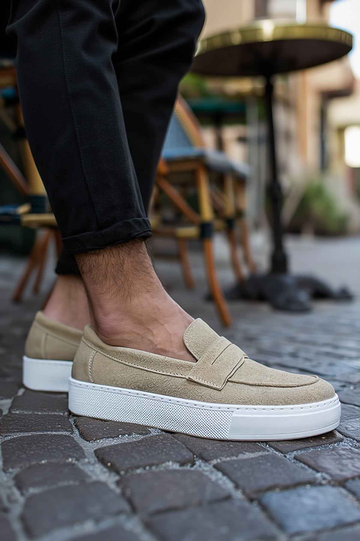 Beige suede loafers on feet, slip-on style with white sole and stitching.