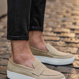 Beige suede loafers with slip-on strap, white sole, casual everyday design.