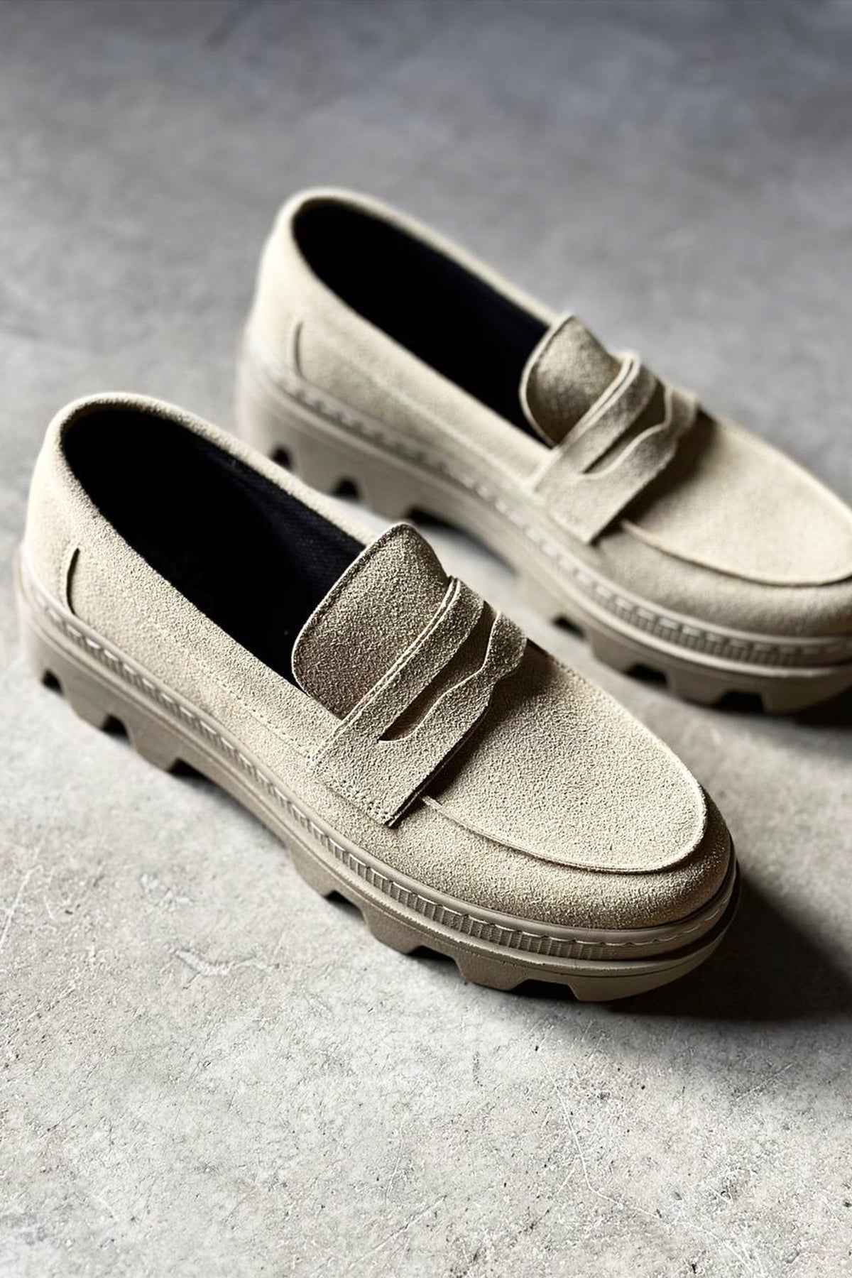 Pair of men's beige suede loafers with strap detail and rubber tread soles