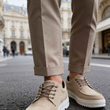 Beige suede lace-up sneakers with thick white sole, on feet