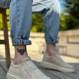 Beige suede slip-on sneakers with white rubber sole, low-profile side branding.