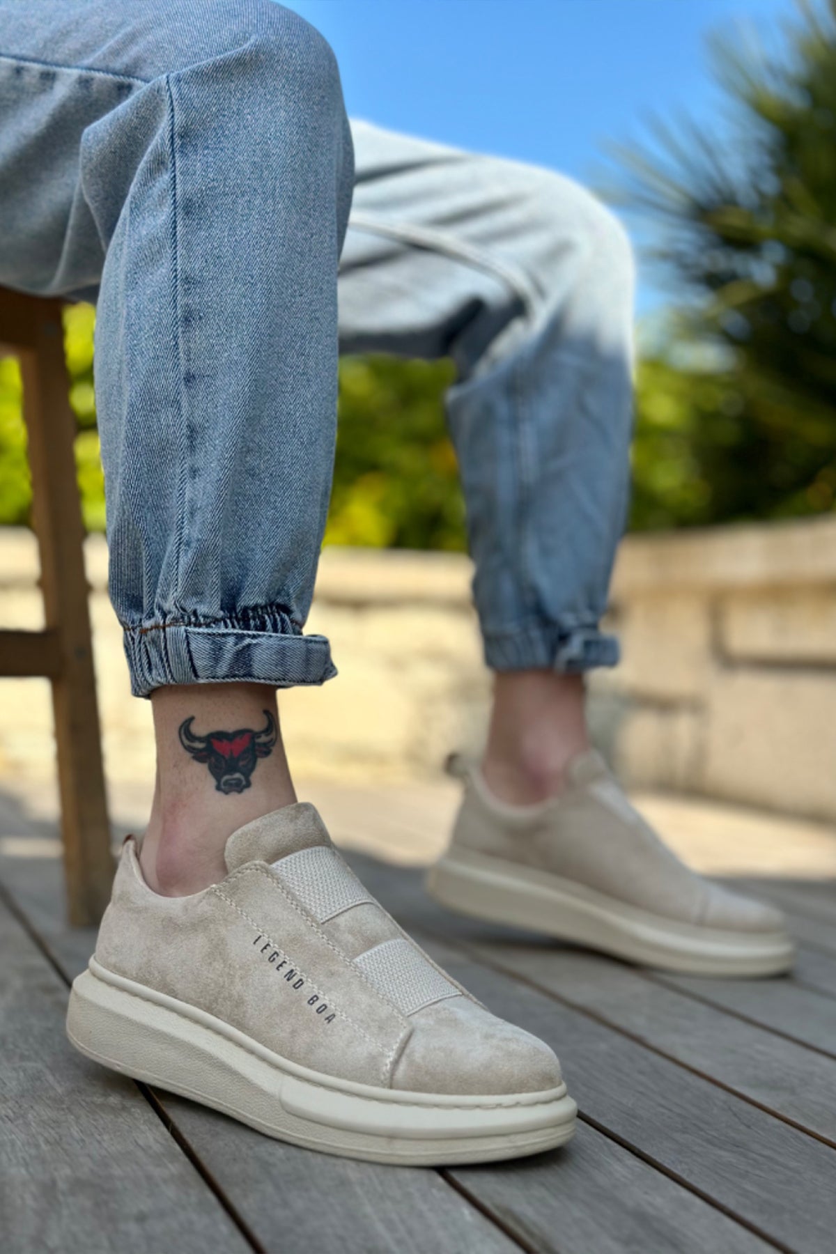 Beige suede slip-on sneakers with white rubber sole, low-profile side branding.