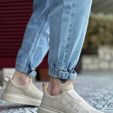Beige suede slip-on sneakers with textured side panel and white sole, no laces.