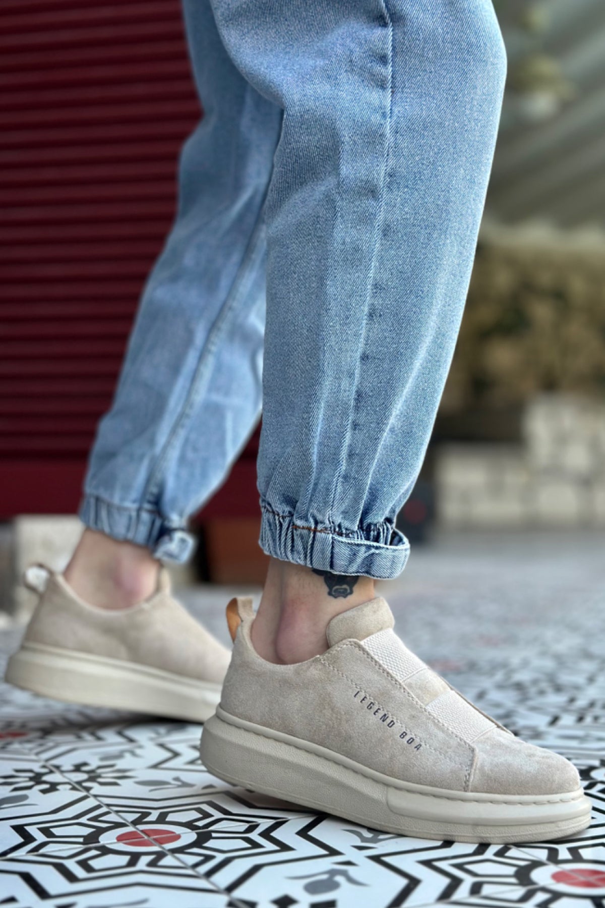 Beige suede slip-on sneakers with textured side panel and white sole, no laces.