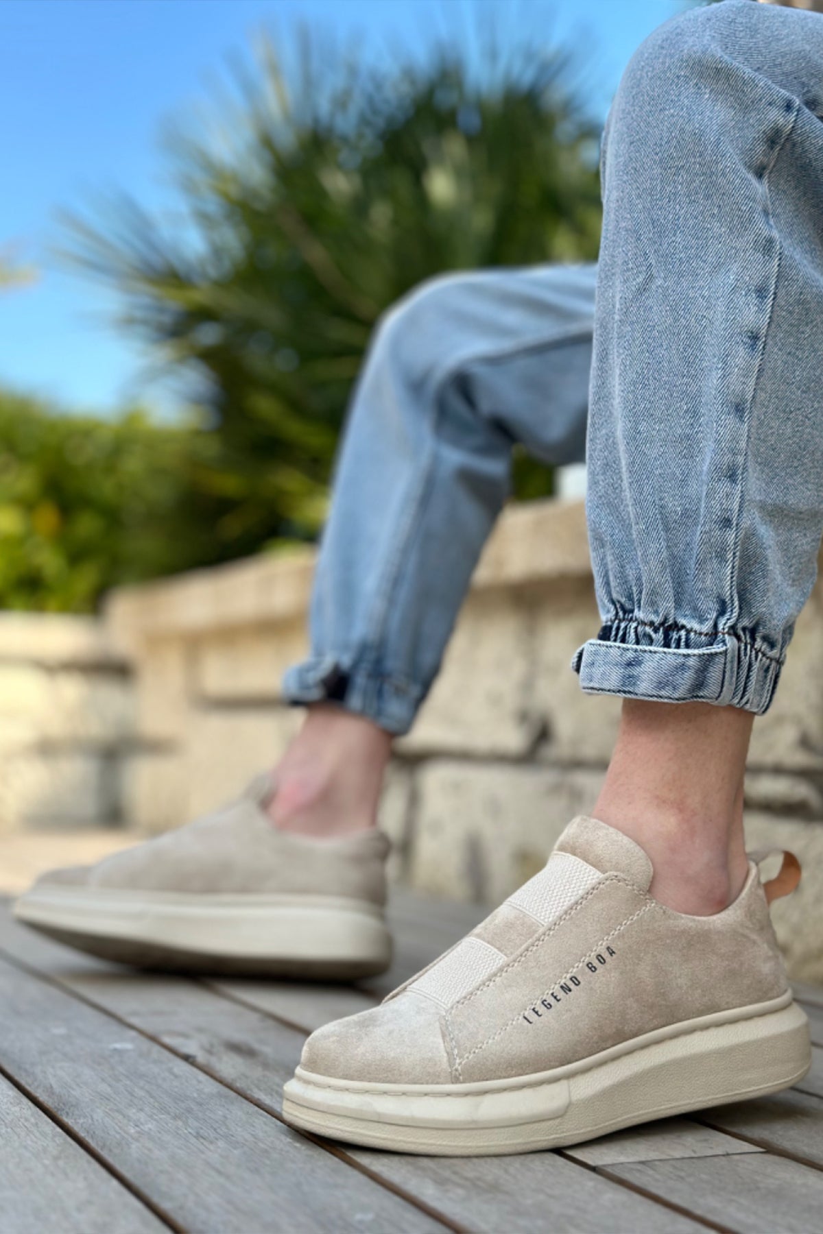 Beige suede slip-on sneakers, rear view with cushioned collar and white sole.