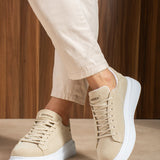 Beige suede low-top sneakers with white rubber sole and lace-up front