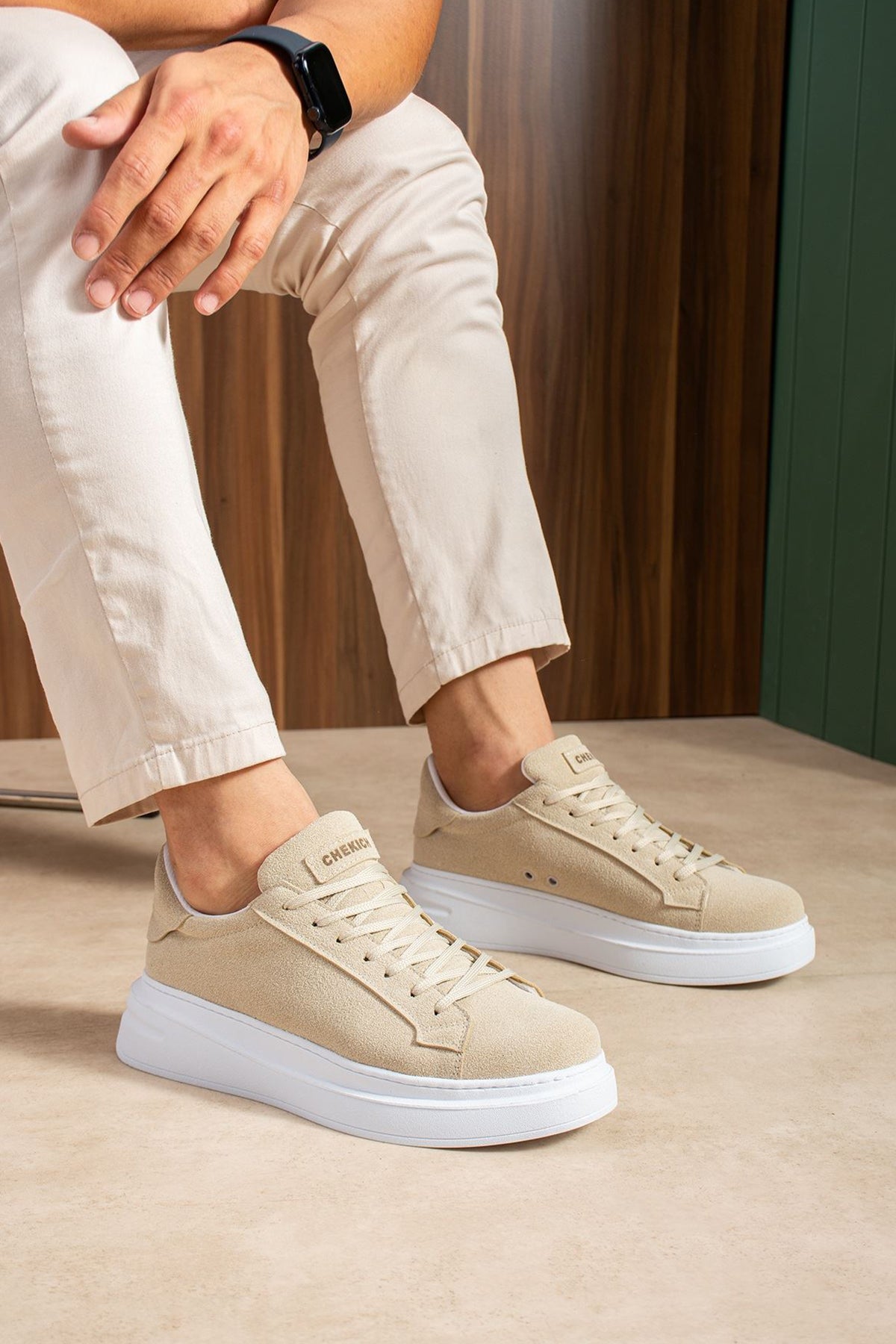 Beige lace-up suede sneakers on white soles worn with light trousers
