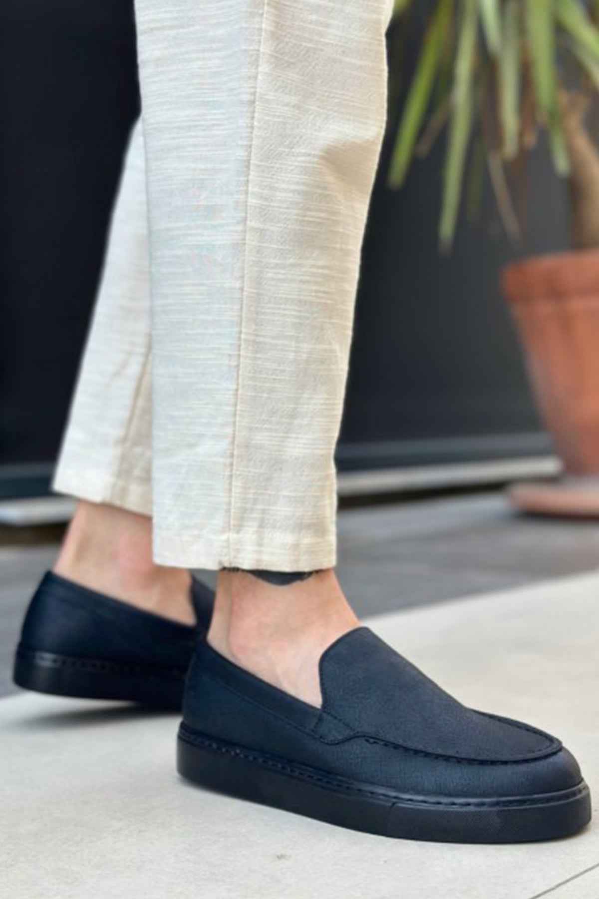Men's black slip-on loafers with smooth upper and stitched detailing at vamp