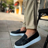 Black slip-on loafers with buckle strap and light blue sole, front view