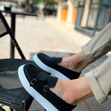 Black loafers with two-buckle strap and light blue sole, close-up top view