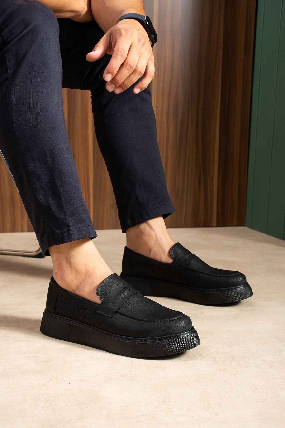 Men's black slip-on loafers with stitched vamp and low-profile sole, angled view