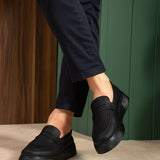 Men's black slip-on loafers with smooth upper and low sole, side close-up